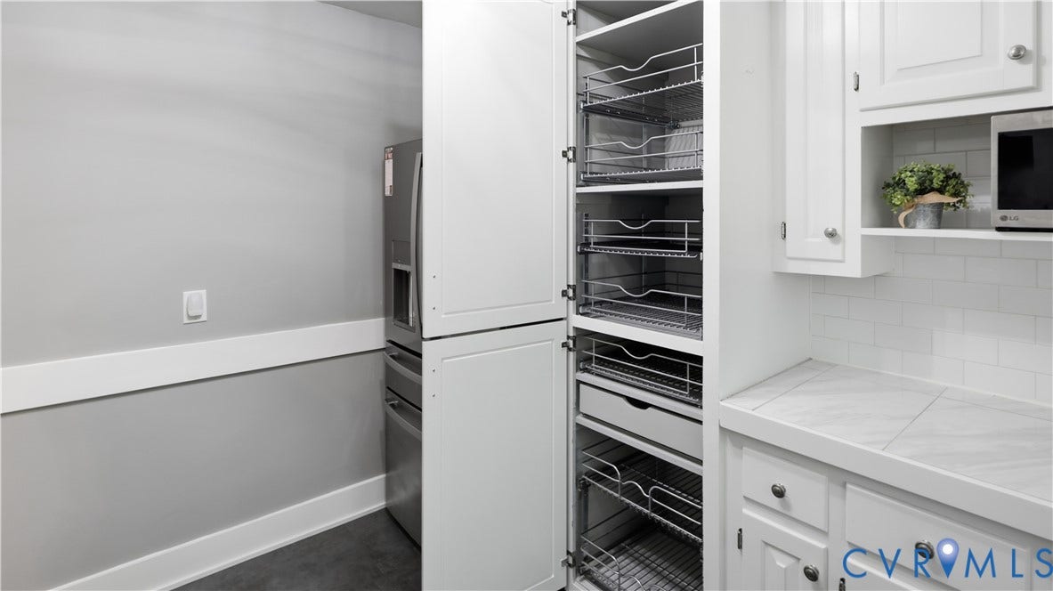 White cabinetry with pull-out wire drawers, subway tile backsplash, and light-toned countertop