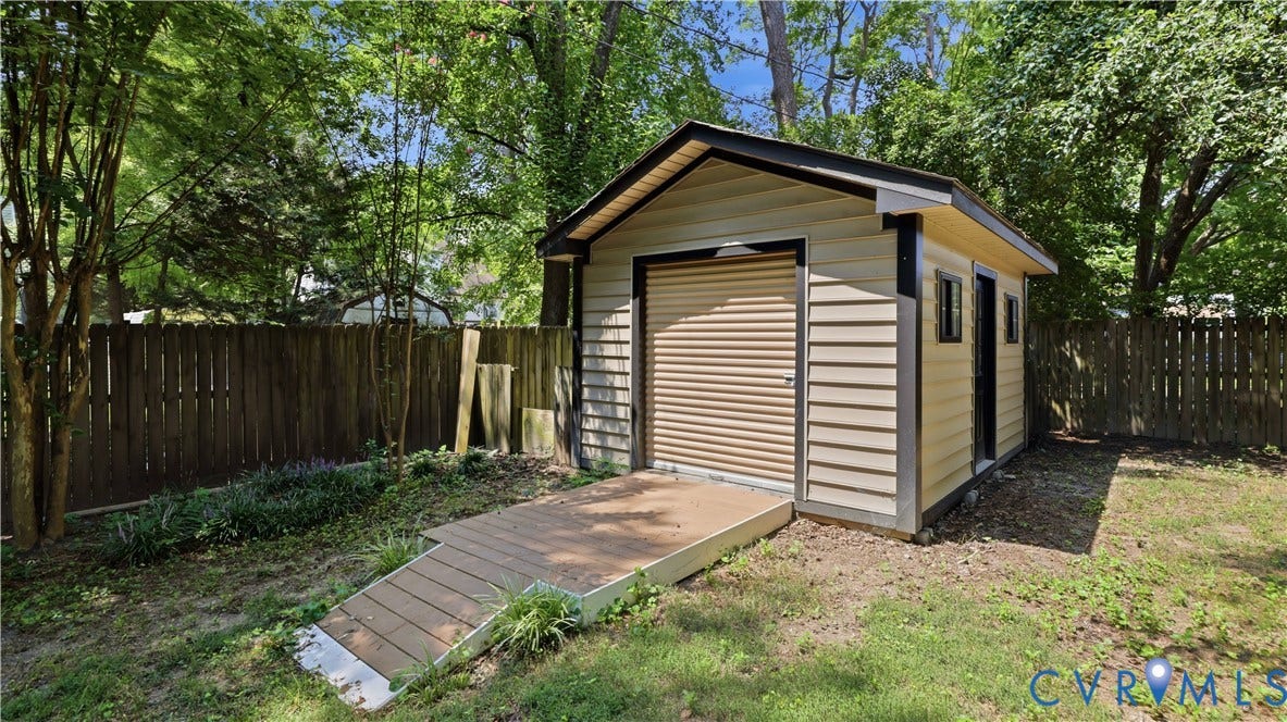 Detached outbuilding with horizontal siding and a black trim, featuring a roll-up door and a side entry