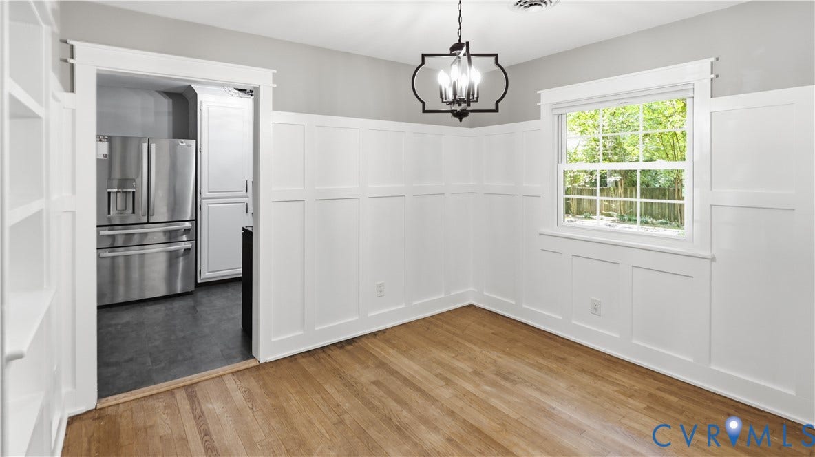 Hardwood flooring, board and batten wall detailing, built-in shelving, black wrought iron chandelier, and a large window