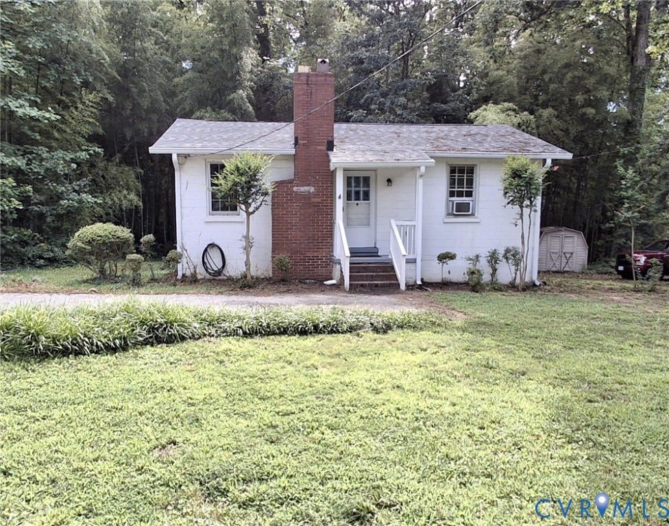 7107 Old Westham Road, Stratford Hills, Richmond, VA 23225 Charming cottage with white exterior and brick chimney detail, set on a manicured lawn bordered by mature trees
