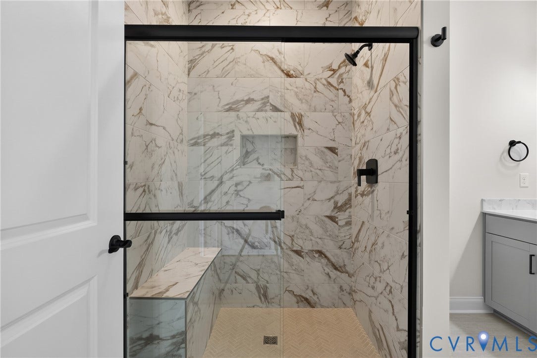 6541 Hardee Haven Place, Midlothian, VA 23112 Glass-enclosed shower with matte black fixtures, full-height tile surround, built-in bench, and a recessed niche