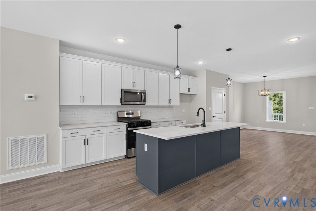 6541 Hardee Haven Place, Midlothian, VA 23112 Kitchen featuring white cabinetry, subway tile backsplash, stainless steel appliances, a center island with a sink, and wood-finish flooring