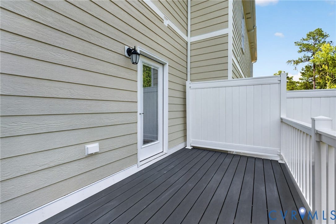 6545 Hardee Haven Place, Midlothian, VA 23112 Deck featuring dark grey composite flooring, white railing, and a privacy wall, with a white exterior door leading to the interior