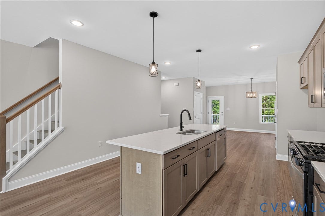 6545 Hardee Haven Place, Midlothian, VA 23112 Open-concept kitchen and living area featuring a large center island with wood-finish cabinetry and white quartz countertop, black gooseneck faucet, and pendant lighting