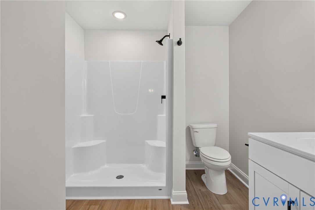 6545 Hardee Haven Place, Midlothian, VA 23112 Walk-in shower with integrated seating, matte black shower fixtures, wood-finish flooring, white vanity with integrated sink, and white toilet