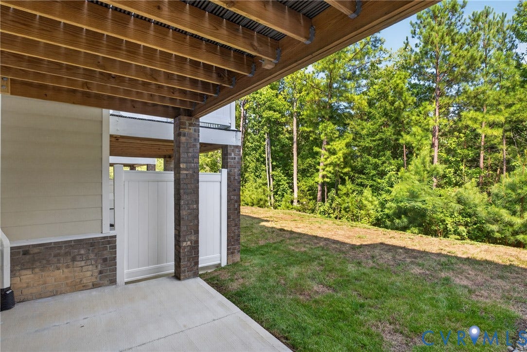 6545 Hardee Haven Place, Midlothian, VA 23112 Concrete patio with a wood-framed deck overhead, brick pillar accents, and a privacy fence