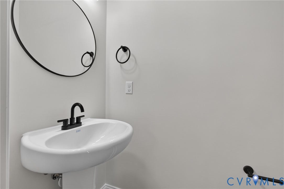 6545 Hardee Haven Place, Midlothian, VA 23112 Pedestal sink with a matte black faucet, wall-mounted mirror, and complementary towel rings