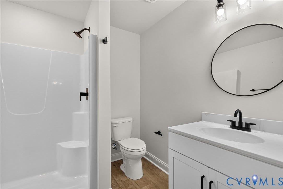 6545 Hardee Haven Place, Midlothian, VA 23112 White vanity with integrated sink and matte black faucet, round wall-mounted mirror, and wood-finish flooring