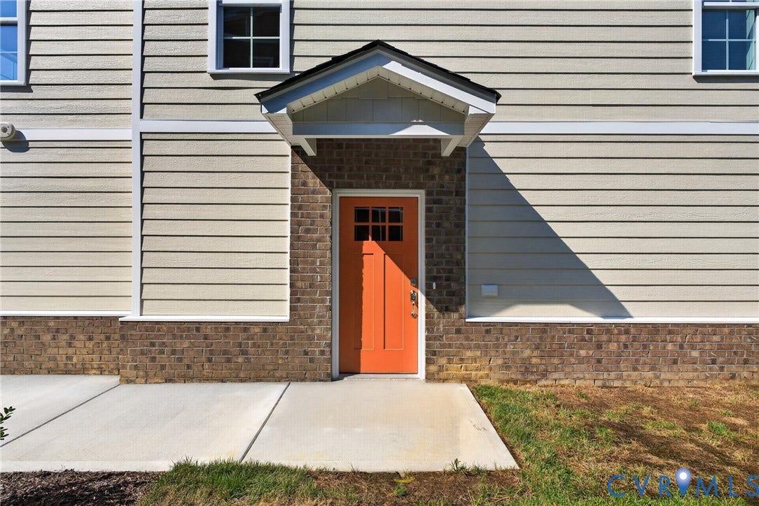 6549 Hardee Haven Place, Midlothian, VA 23112 Exterior facade featuring horizontal siding, brick wainscoting, an orange paneled entry door, and a covered entry