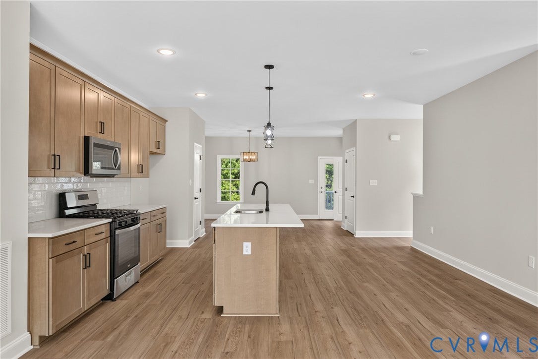 6549 Hardee Haven Place, Midlothian, VA 23112 Kitchen featuring light wood-finish cabinetry, white subway tile backsplash, stainless steel appliances, and a central island with a sink and pendant lighting