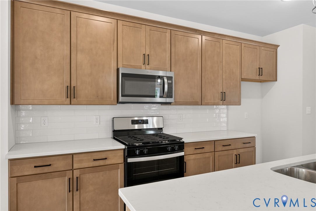 6549 Hardee Haven Place, Midlothian, VA 23112 Wood-finish cabinetry, stainless steel microwave, white subway tile backsplash, white countertops, and stainless steel gas range