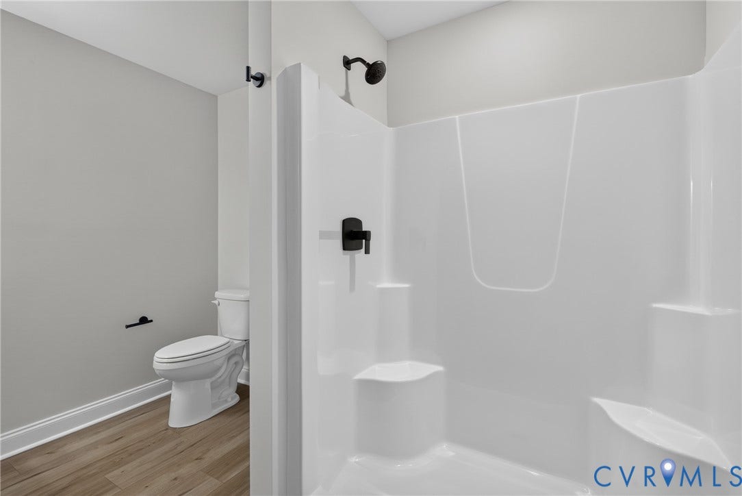 6549 Hardee Haven Place, Midlothian, VA 23112 White shower enclosure with integrated shelving and seating, matte black shower fixtures, wood-finish flooring, and white toilet