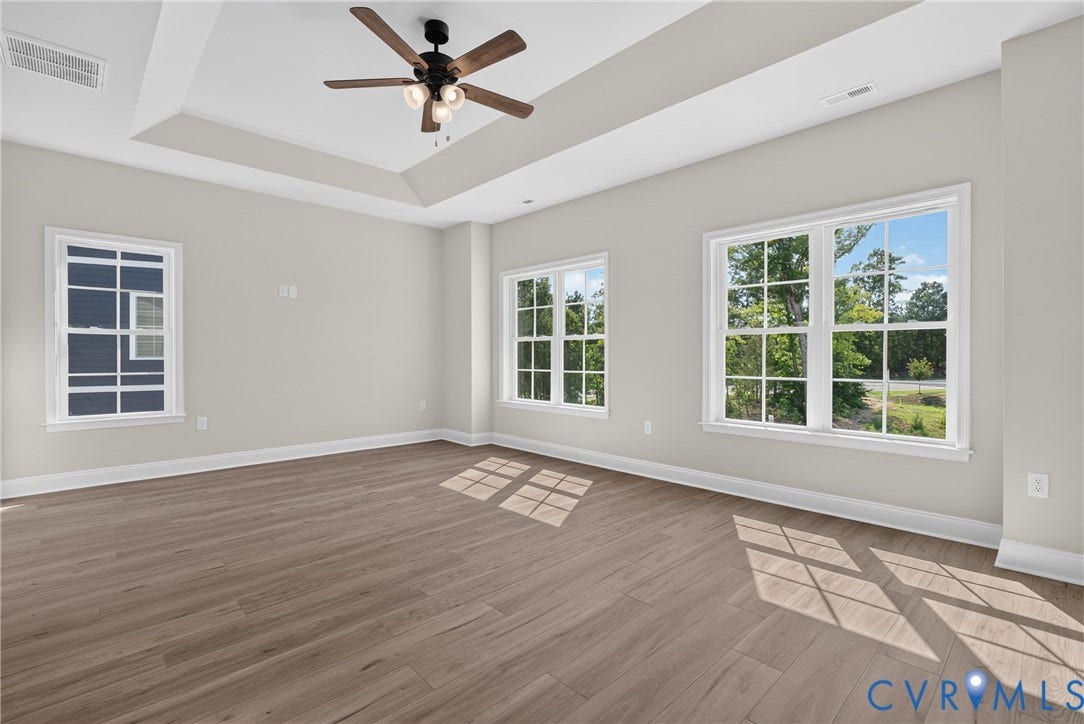 6549 Hardee Haven Place, Midlothian, VA 23112 Spacious room featuring a tray ceiling, ceiling fan, wood-finish flooring, and multiple windows