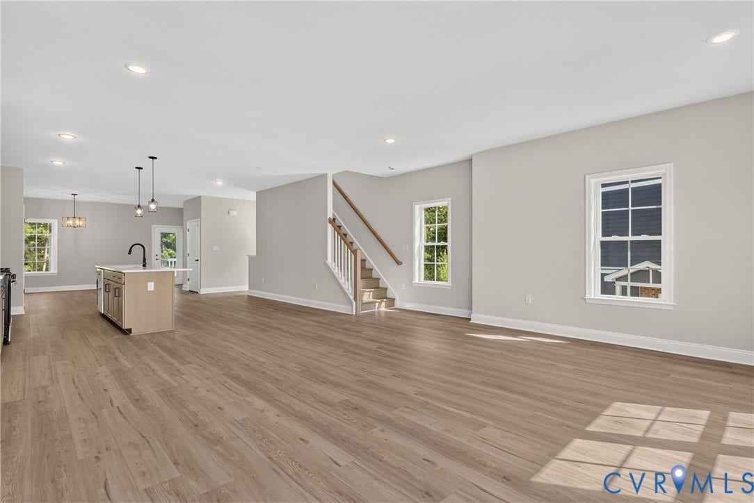 6549 Hardee Haven Place, Midlothian, VA 23112 Open-concept living area featuring wood-finish flooring, recessed lighting, a central kitchen island with a dark faucet, and a stairway with white balusters