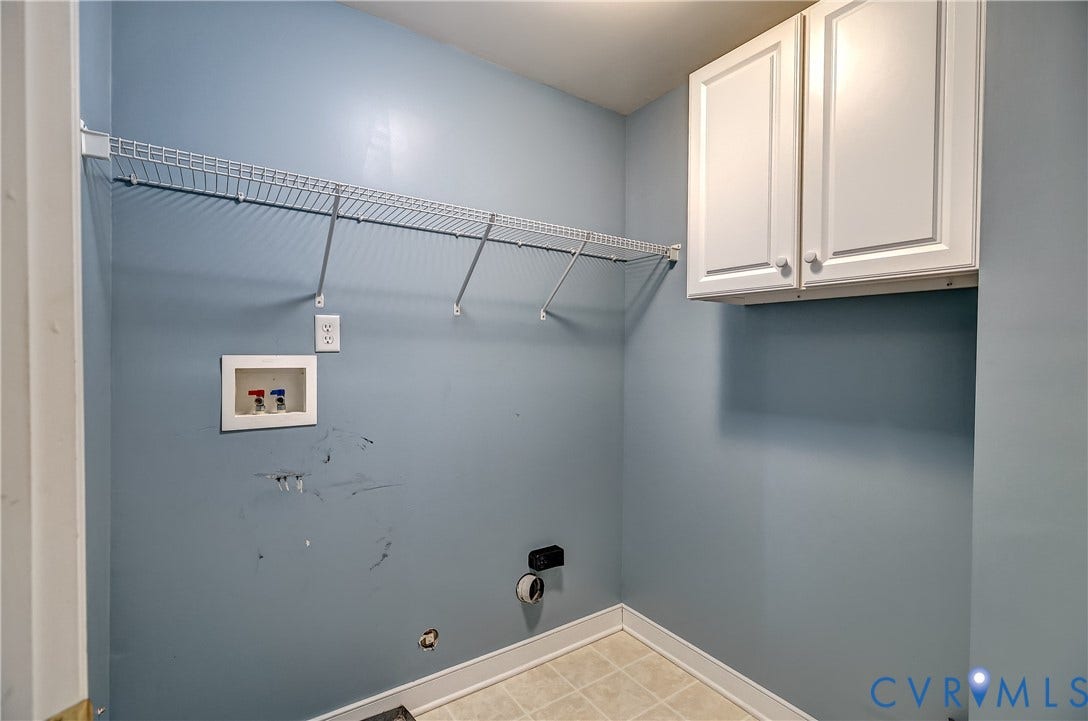 Laundry area featuring wall-mounted wire shelving, white cabinetry, and utility hookups