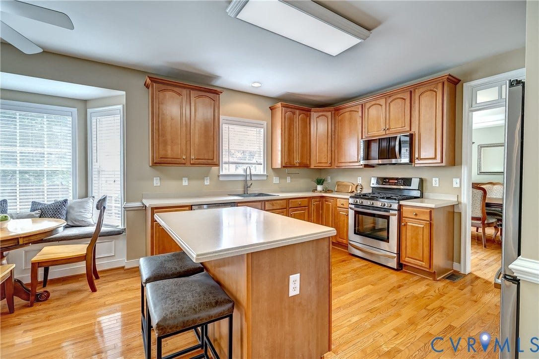 Kitchen featuring wood-finish flooring, light-toned cabinetry, stainless steel appliances, and a central island perfect for entertaining or grab and go eating.
