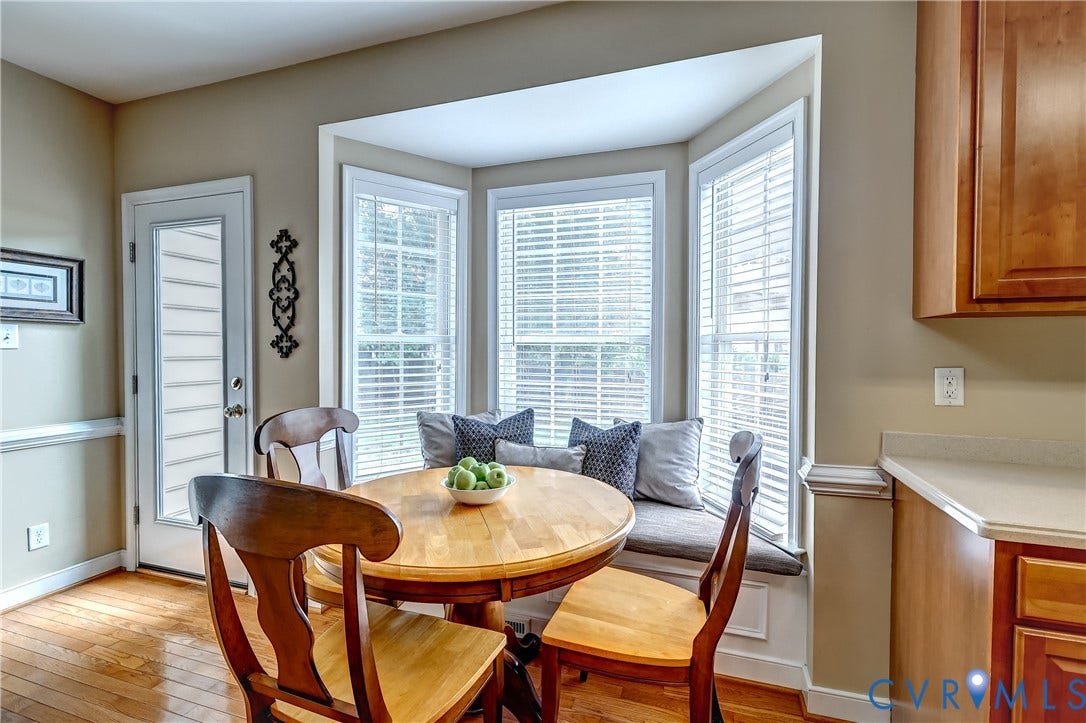 Bay window with built-in bench seating, wood-finish flooring, and natural wood cabinetry