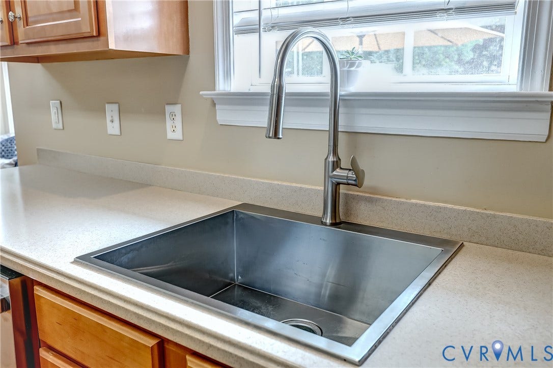 Undermount stainless steel sink with a high-arc faucet, set into a light-toned countertop