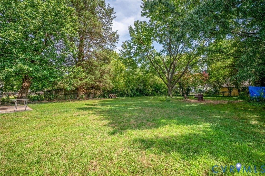 4819 Arundel Avenue, Chesterfield, VA 23234 Expansive green lawn surrounded by mature trees, featuring a concrete patio