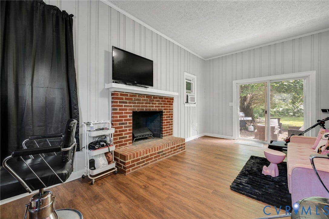 4819 Arundel Avenue, Chesterfield, VA 23234 Brick fireplace with a white mantel, wood-finish flooring, and sliding glass doors to the exterior