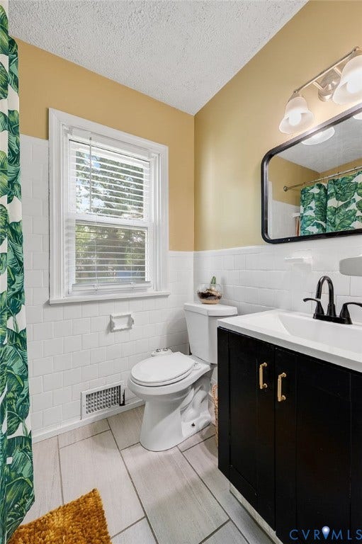 4819 Arundel Avenue, Chesterfield, VA 23234 White subway tile wainscoting, light wood-look tile flooring, black vanity with gold-tone hardware, and a framed mirror