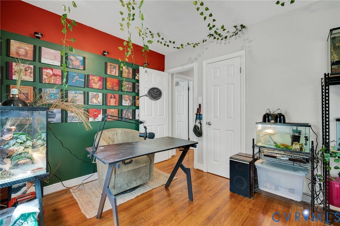4819 Arundel Avenue, Chesterfield, VA 23234 Creative home office featuring warm wood-finish flooring, custom green built-in wall shelving with red accent paneling, white six-panel closet doors, and black hardware accents throughout the space