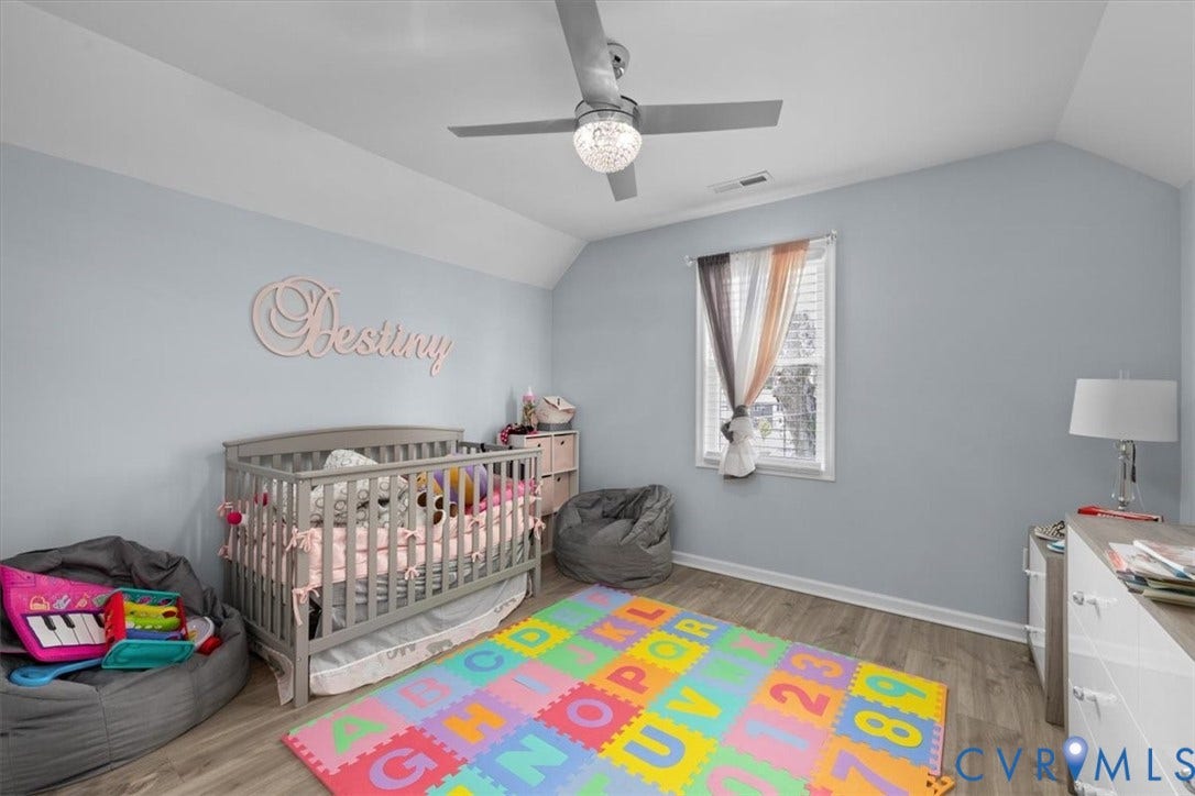 Wood-finish flooring, light blue wall paint, and a ceiling fan with integrated lighting