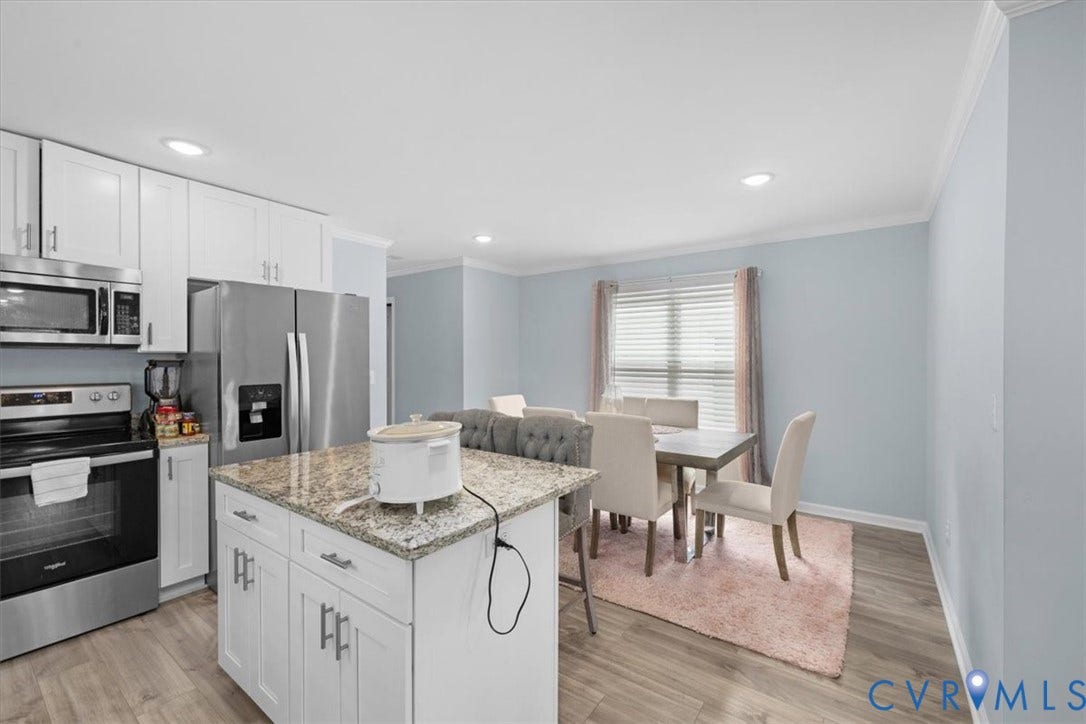 Kitchen featuring white cabinetry with stainless steel appliances, a center island with a granite countertop, and wood-finish flooring
