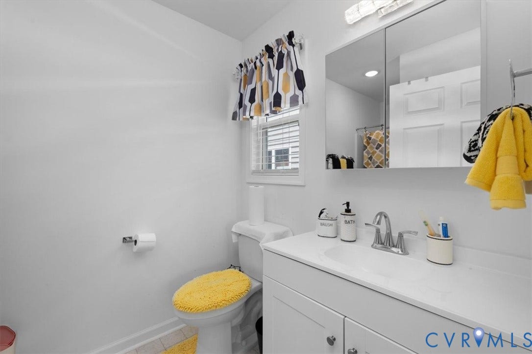 White vanity with integrated sink, chrome faucet, and mirrored medicine cabinet
