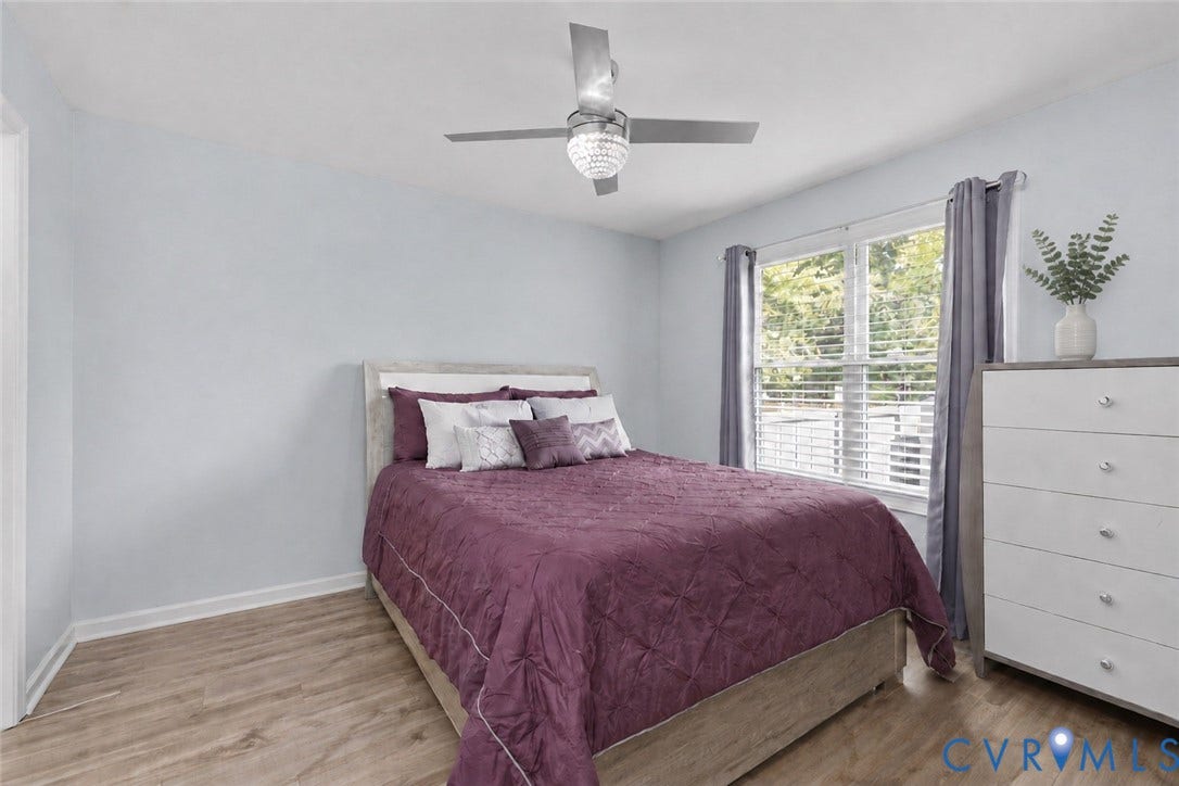 Recessed window with blinds, wood-finish flooring, ceiling fan with crystal detail, and light-colored walls