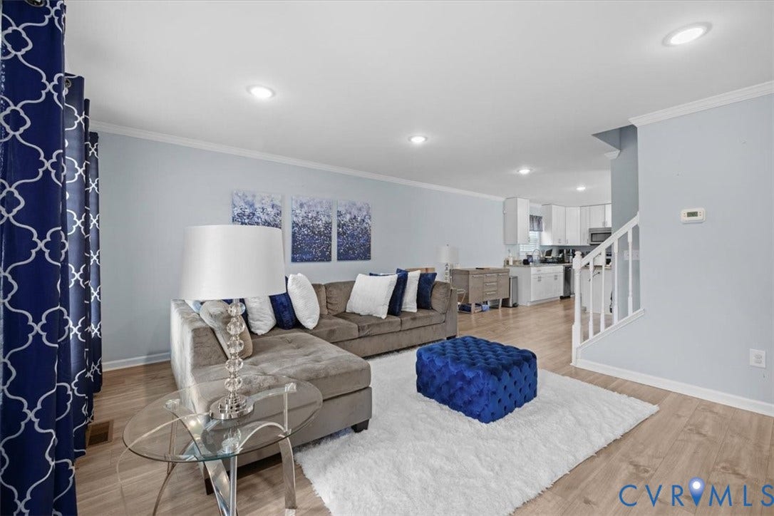 Recessed ceiling lighting, crown molding, wood-finish flooring, white kitchen cabinetry, and white stair railing
