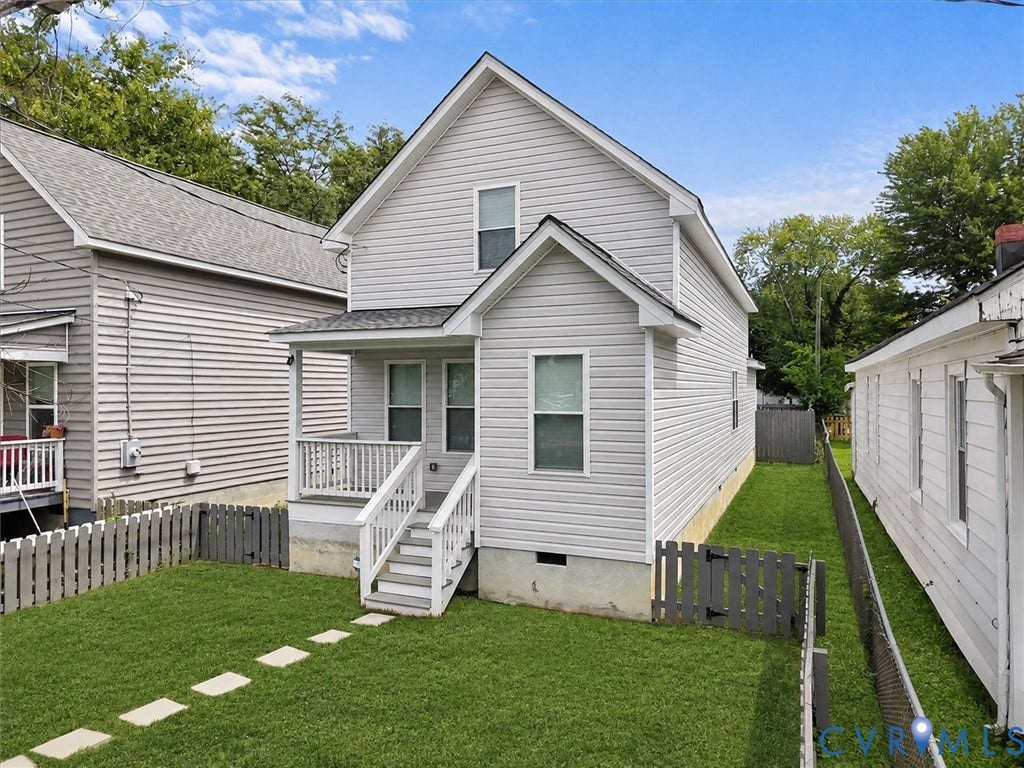 Two-story home featuring light-toned horizontal siding, a covered entry porch with white railings, and a shingled roof