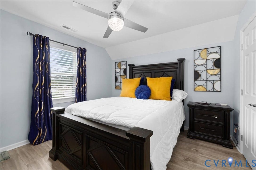 Wood-finish flooring, recessed window with blinds, ceiling fan with light fixture, and paneled door