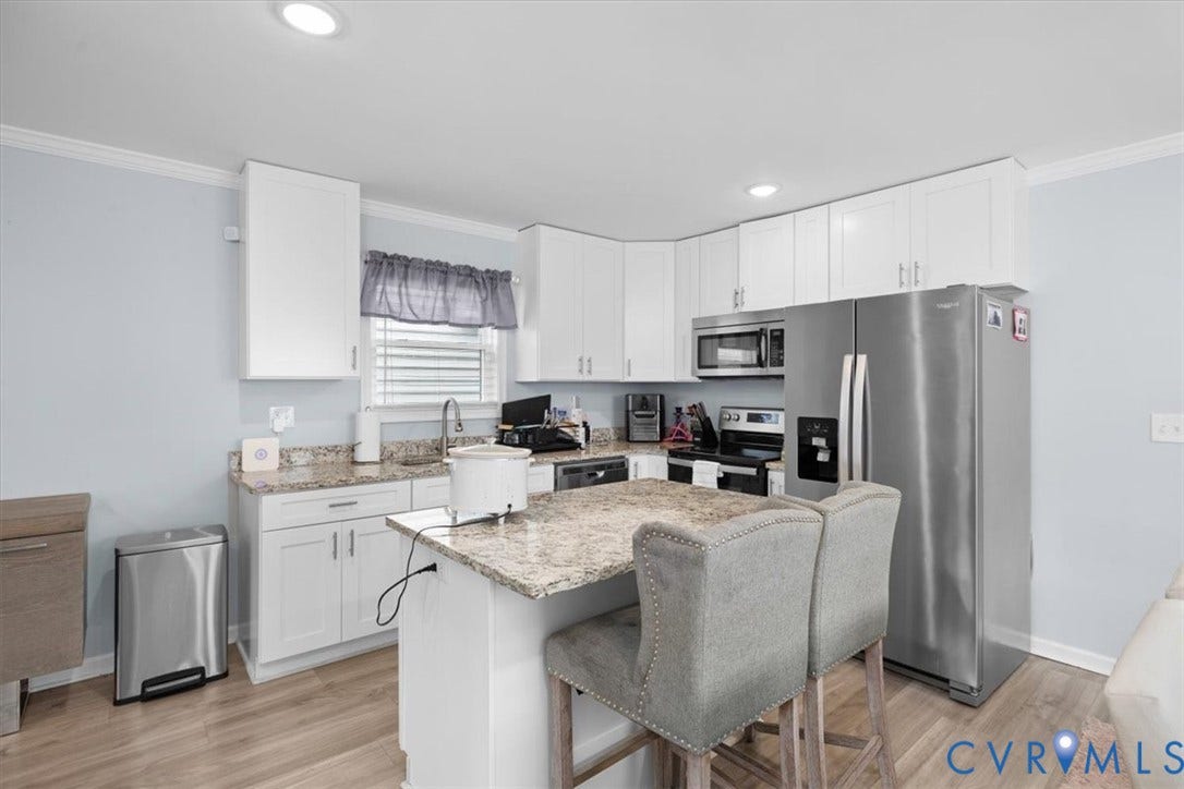 Contemporary kitchen featuring white cabinetry, light-toned countertops, wood-finish flooring, and recessed lighting