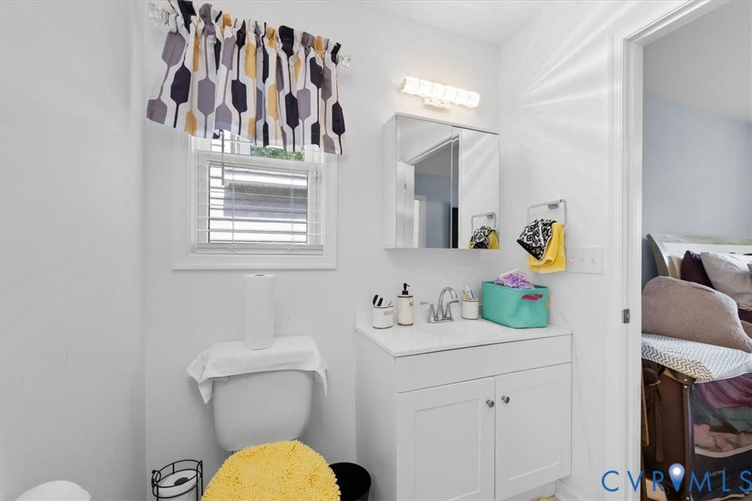 White vanity with integrated sink, chrome faucet, wall-mounted mirror cabinet, and overhead light fixture