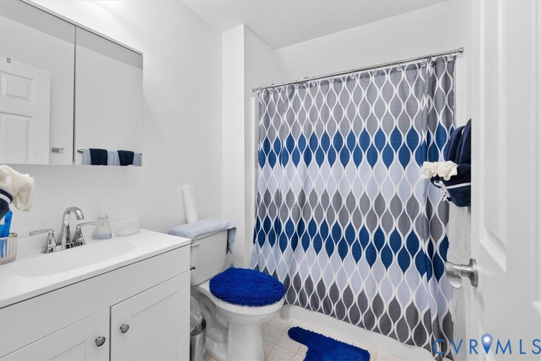 White vanity with integrated sink, chrome faucet, and mirrored medicine cabinet