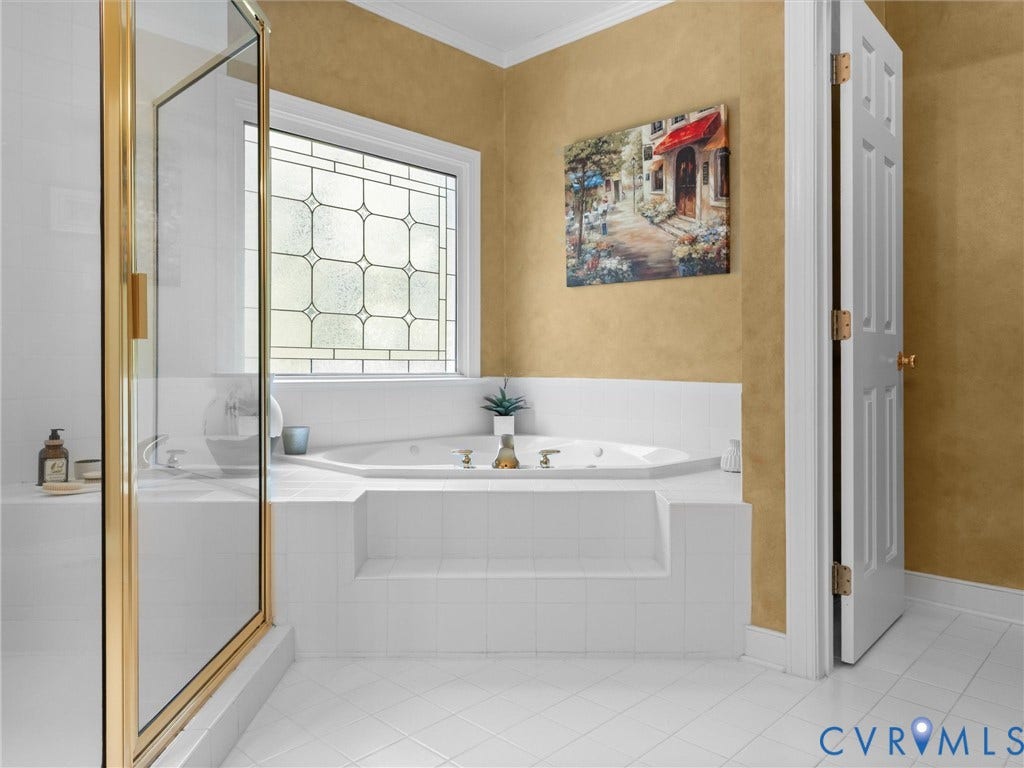 15706 Fox Marsh Drive, Moseley, VA 23120 Soaking tub with tiled surround, leaded glass window, and a glass-enclosed shower with gold-tone framing