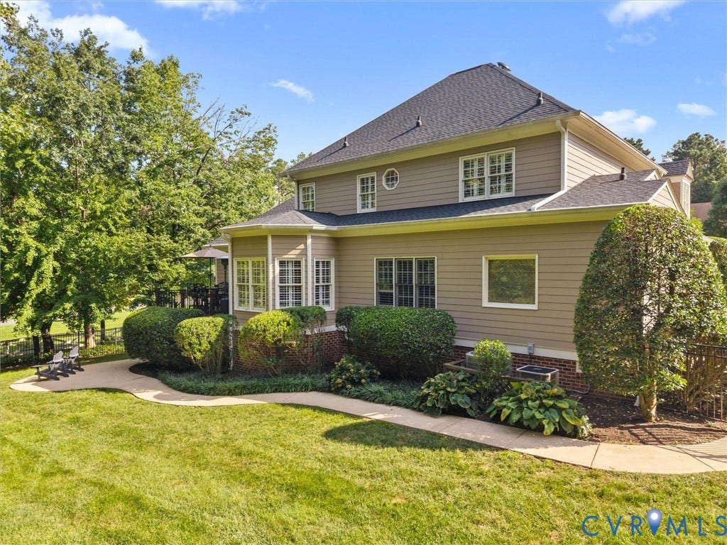 15706 Fox Marsh Drive, Moseley, VA 23120 Expansive backyard featuring a manicured lawn, curved concrete pathway, and mature landscaping