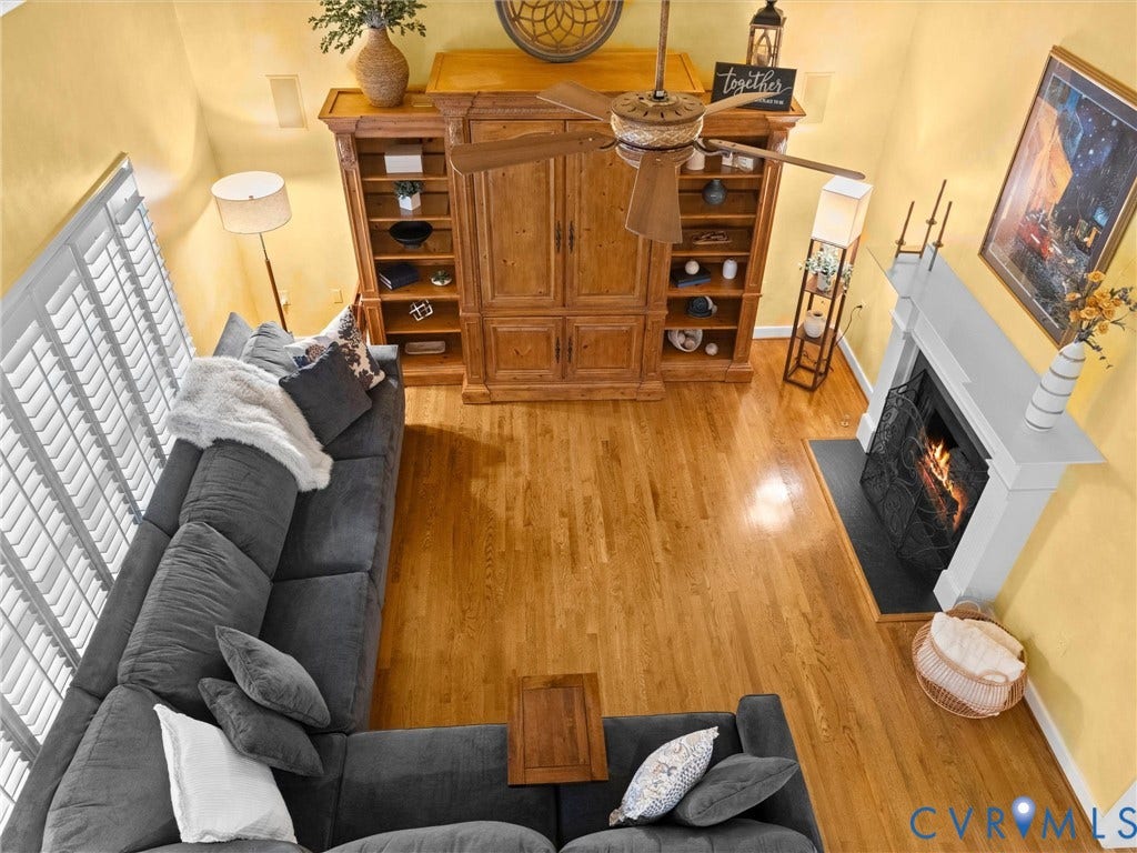15706 Fox Marsh Drive, Moseley, VA 23120 Hardwood flooring, fireplace with a white mantel, ceiling fan, built-in shelving, and plantation shutters
