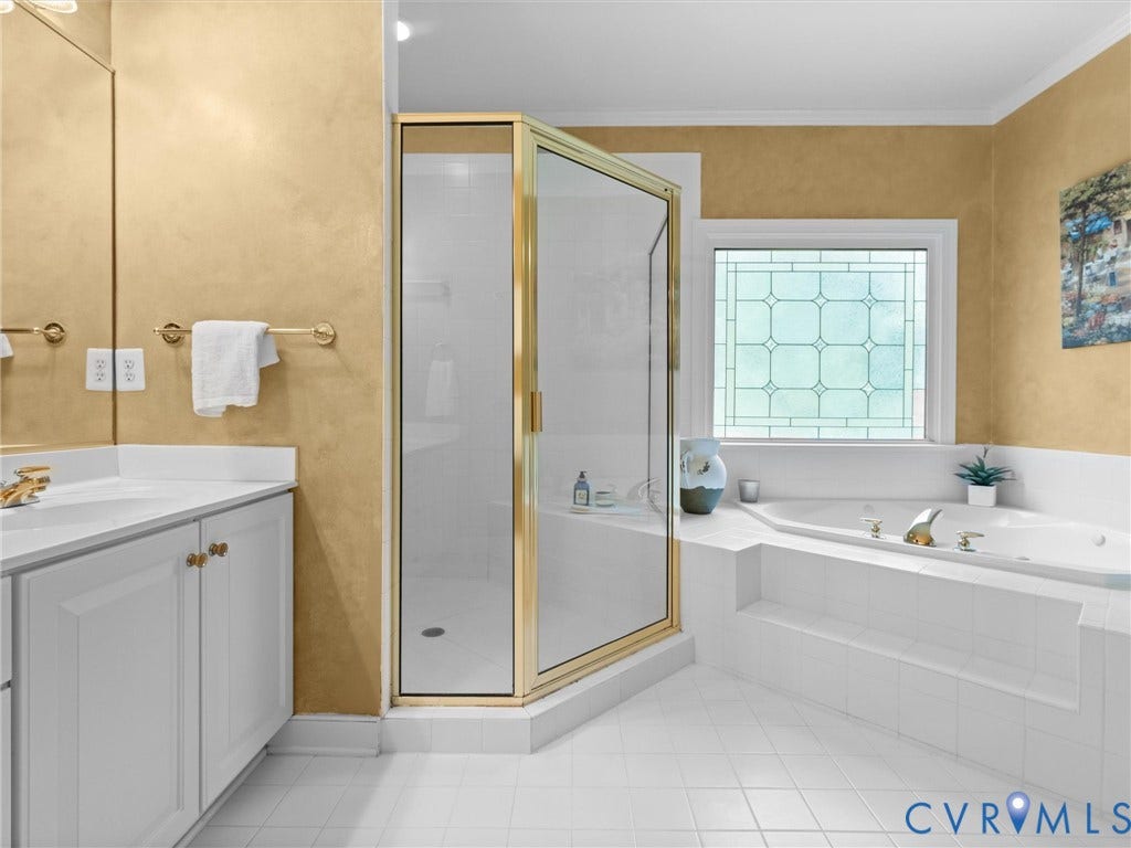 15706 Fox Marsh Drive, Moseley, VA 23120 Spacious bathroom featuring a built-in soaking tub, corner shower with brass-finish frame, leaded glass window, and a white vanity with integrated sink