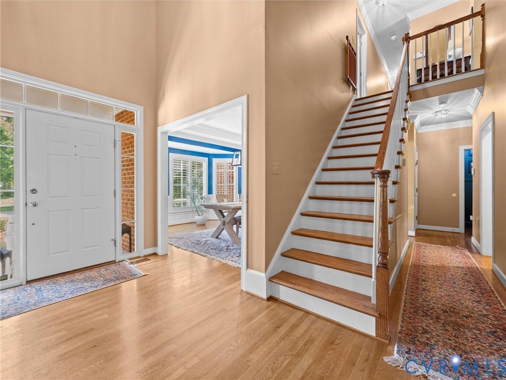 15706 Fox Marsh Drive, Moseley, VA 23120 Two-story foyer with wood-finish flooring, a white paneled entry door with sidelights and transom, and a staircase with wood treads and banister