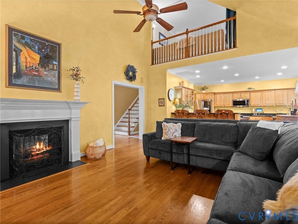 15706 Fox Marsh Drive, Moseley, VA 23120 Hardwood flooring, a fireplace with a white mantel, and a kitchen featuring wood cabinetry and stainless steel appliances
