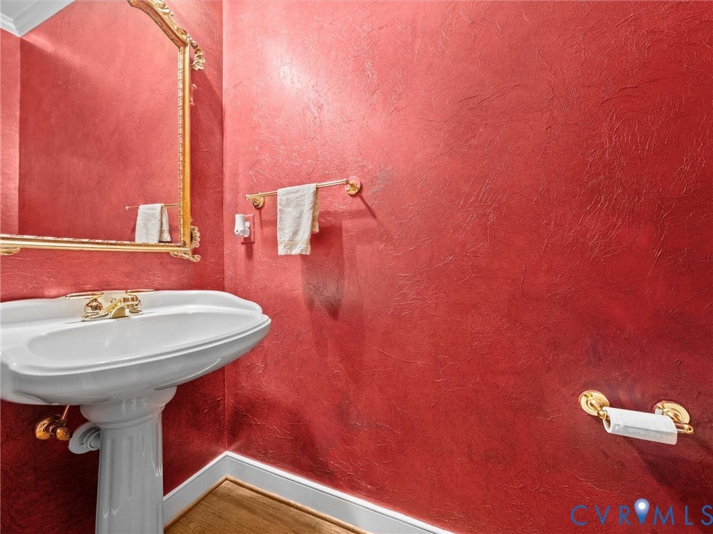 15706 Fox Marsh Drive, Moseley, VA 23120 Pedestal sink with brass-finish faucet, ornate mirror, textured red walls, and wood-finish flooring