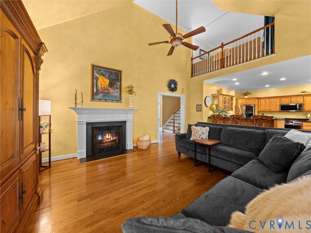 15706 Fox Marsh Drive, Moseley, VA 23120 Vaulted ceiling, wood-finish flooring, white mantel fireplace, open concept kitchen, and upper-level railing