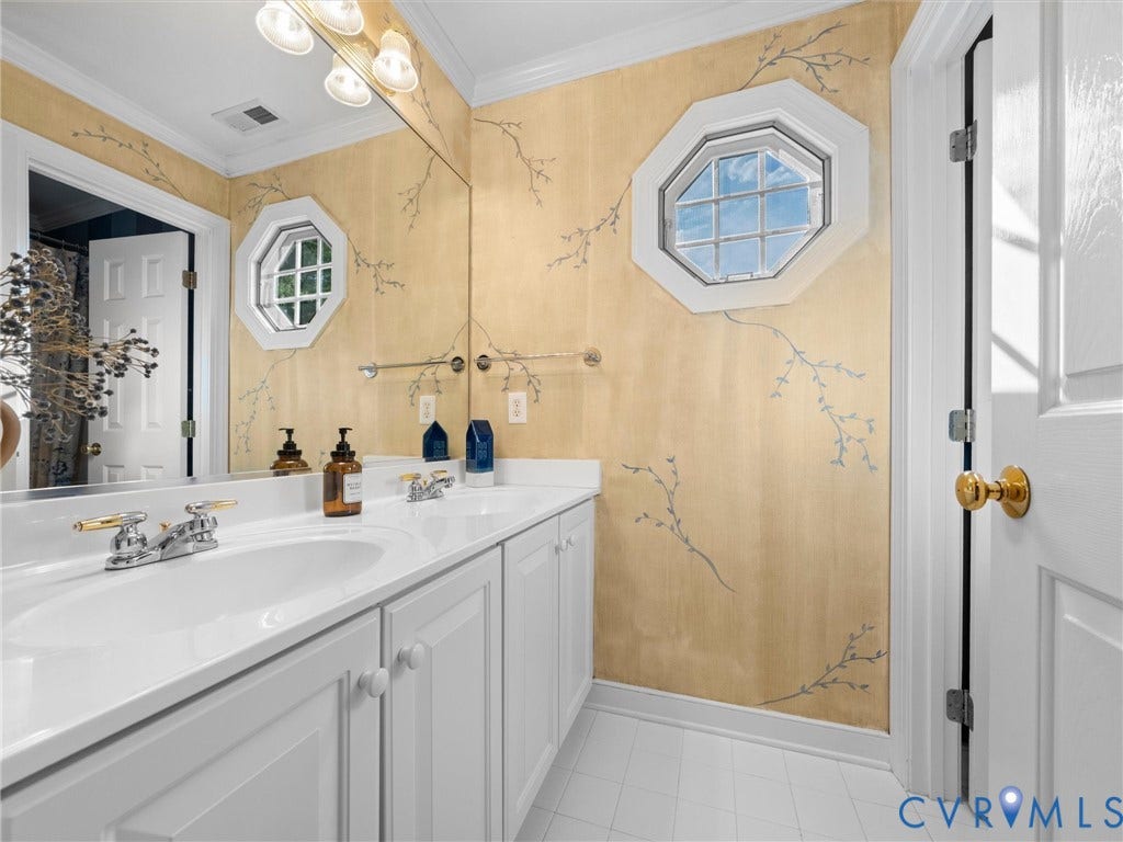 15706 Fox Marsh Drive, Moseley, VA 23120 Dual vanity with white cabinetry and integrated sinks, accented by a full-width mirror and octagonal window