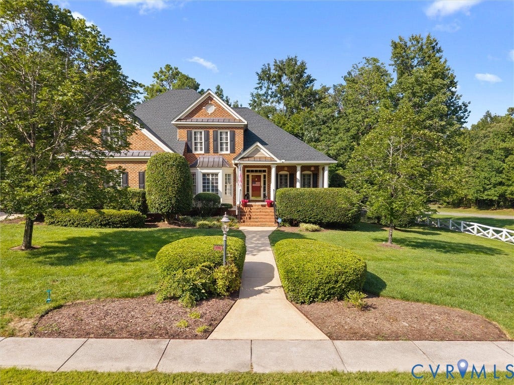 15706 Fox Marsh Drive, Moseley, VA 23120 Brick exterior with white trim, covered front porch, gabled roof, established landscaping, and a concrete walkway