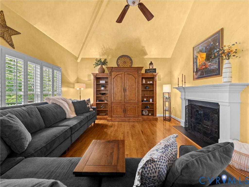 15706 Fox Marsh Drive, Moseley, VA 23120 Vaulted ceiling, wood-finish flooring, white plantation shutters, built-in cabinetry, and a fireplace with a decorative mantel