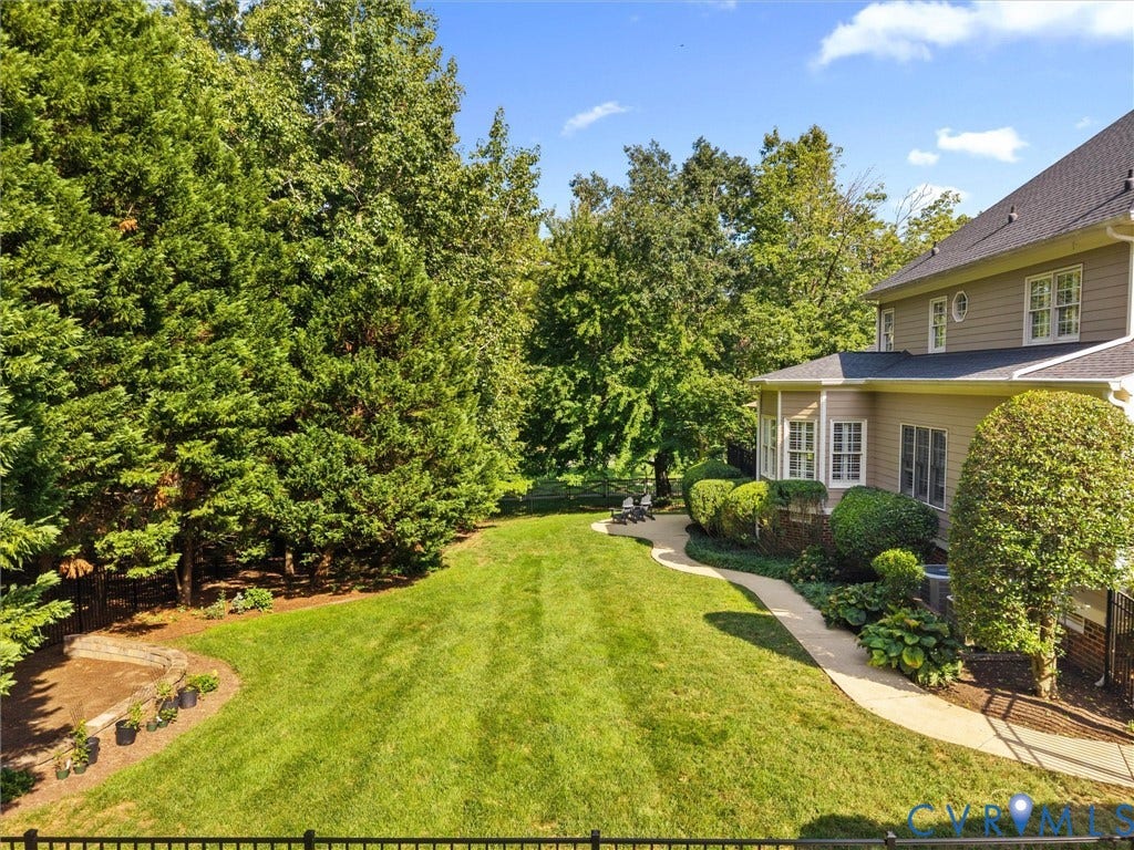 15706 Fox Marsh Drive, Moseley, VA 23120 Expansive backyard featuring a manicured lawn, established perimeter trees, and a curved paved walkway