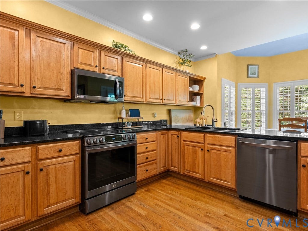 15706 Fox Marsh Drive, Moseley, VA 23120 Wood-finish flooring, wood cabinetry, dark countertops, stainless steel appliances, and plantation shutters