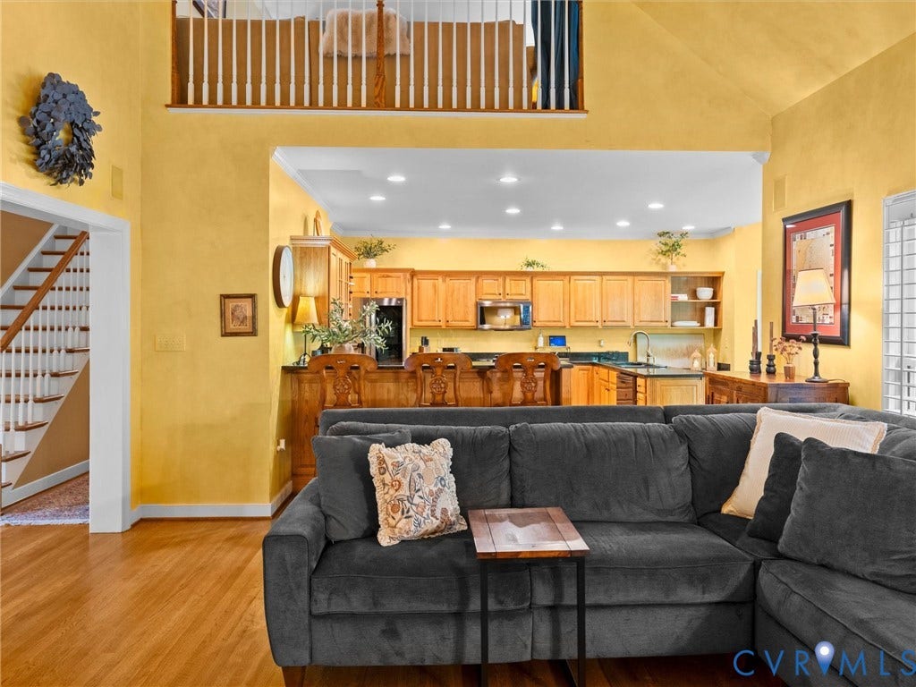 15706 Fox Marsh Drive, Moseley, VA 23120 Hardwood flooring, two-story ceiling, kitchen with wood cabinetry, stainless steel appliances, and a breakfast bar
